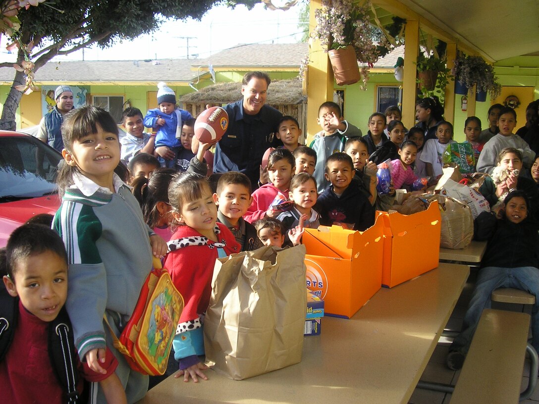 Chris Hilde, firefighter, Marine Corps Air Station Miramar, stands in the background amongst the children at Casa Hogar Belen Orphanage, in Tijuana, Mexico, after handing out toys Dec. 10, 2005. Though Miramar?s Fire Department adopted the orphanage for the holidays, Hilde plans on visiting again.