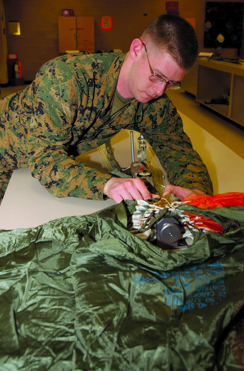 Gunnery Sgt. William T. Campbell, Marine Aviation Logistics Squadron 13 Aviation Life Support Systems division chief, prepares a ballistic spreader gun on a parachute for testing at the station parachute loft Jan. 13.