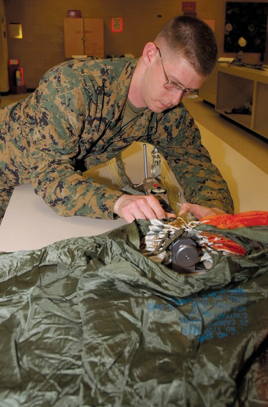 Gunnery Sgt. William T. Campbell, Marine Aviation Logistics Squadron 13 Aviation Life Support Systems division chief, prepares a ballistic spreader gun on a parachute for testing at the station parachute loft Jan. 13.