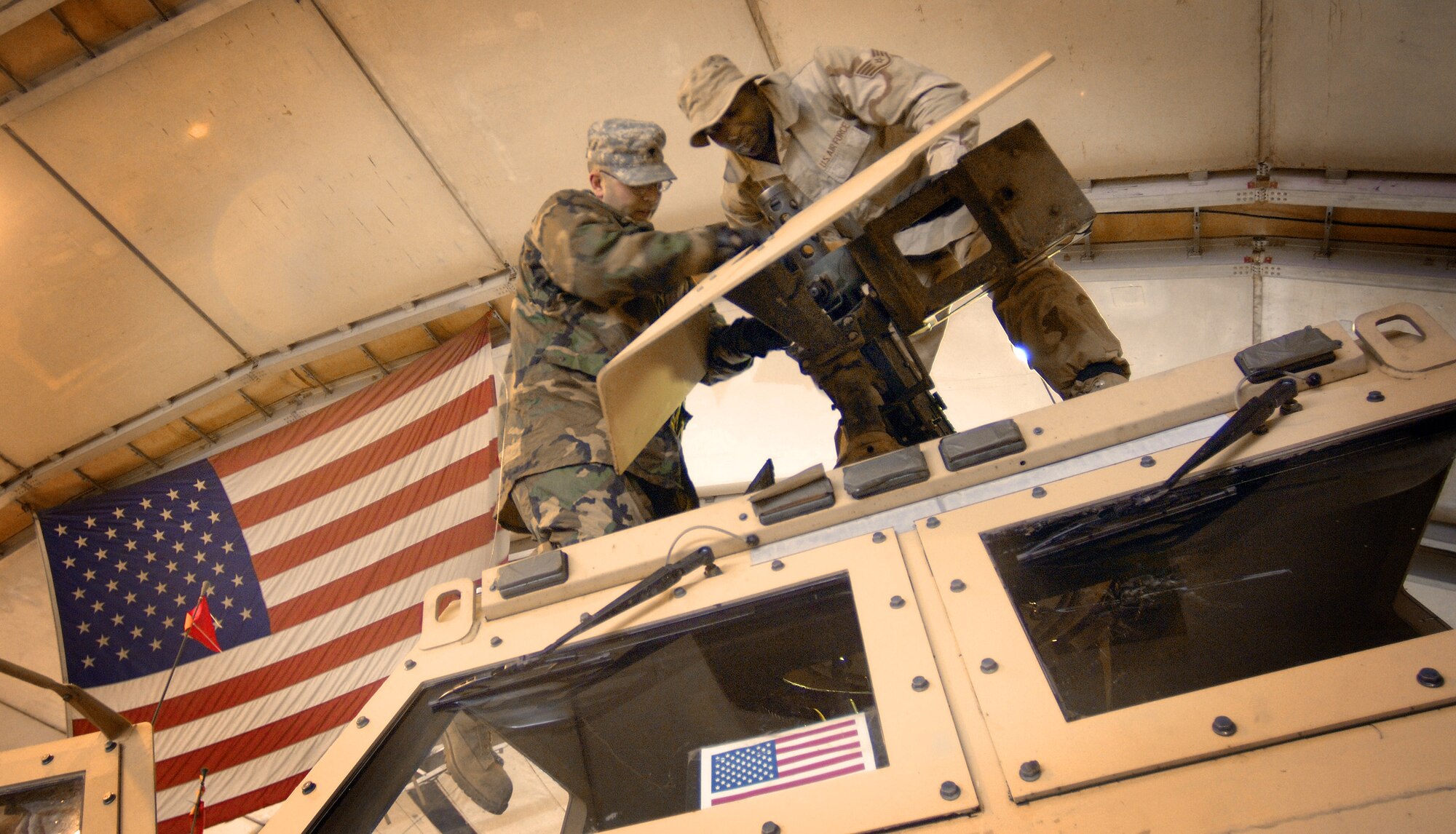 BALAD AIR BASE, Iraq (AFPN) - Staff Sgt. Lee Moses (right) teaches Army Spc. Thomas Brey how to dismount a 50-caliber machine gun on an armored truck turret. The Airman and Soldier are with the 723rd Expeditionary Logistics Readiness Squadron. The unit achieved its 4-millionth convoy mile. The first convoy began two years ago. (U.S. Air Force photo by Master Sgt. Lance Cheung)