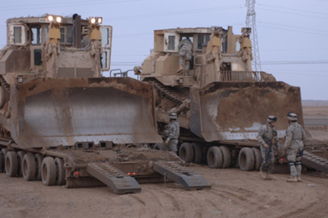 U.S. Army soldiers from Alpha Company, 3rd Special Troops Battalion, 3rd Brigade, 101st Airborne Division prepare to unload two armored Caterpillar D9 bulldozers from their carriers at Al Butoma, Iraq, on Jan. 11, 2006. The soldiers will use the bulldozers to construct berms for security in Al Butoma. 