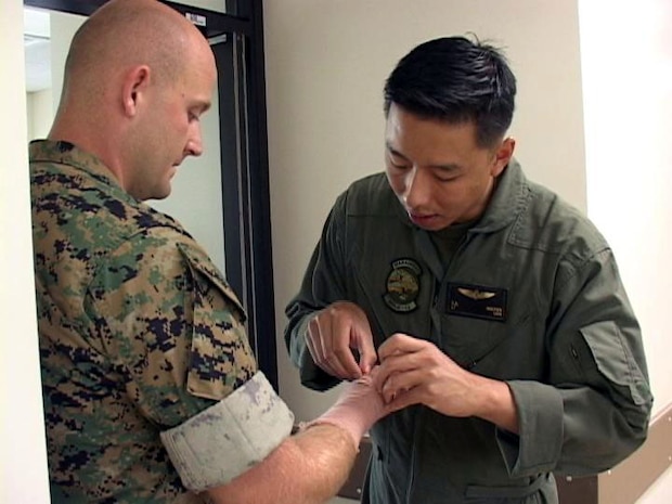 Lt. Khanh X. Nguyen, Marine Aviation Logistics Squadron 12 flight surgeon and native of San Jose, Calif., treats Sgt. William D. Smith for an injury in his right hand. Smith, who is a MALS-12 support equipment mechanic and native of Stephenville, Texas, had his wrist X-rayed for a possible fracture.