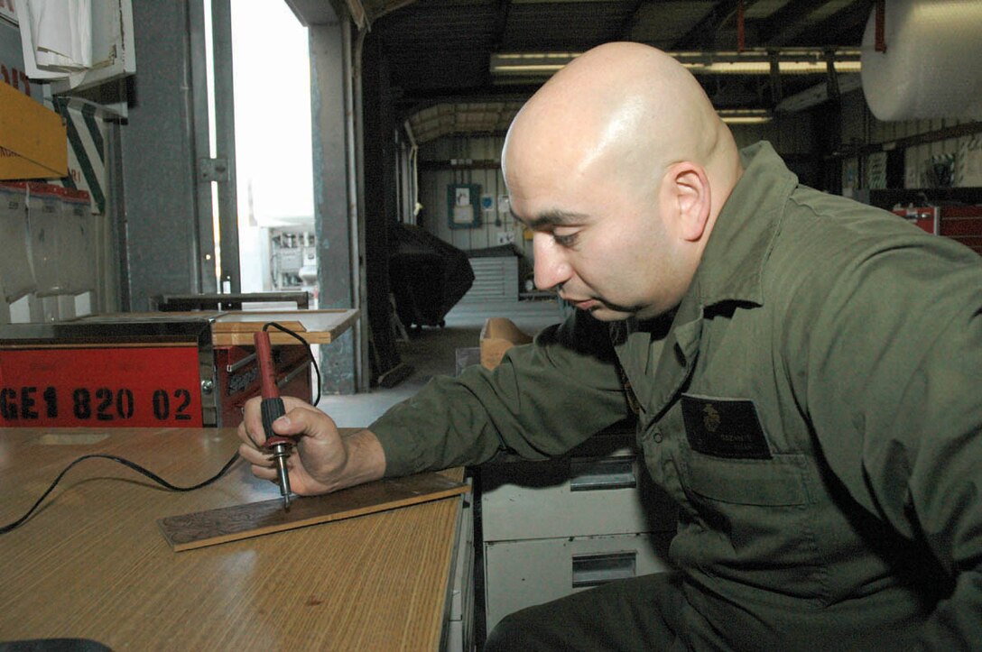 Sgt. Alejandro Bazante, Marine Aviation Logistics Squadron 13 cryogenics technician, decorates a board with pyrography, or wood burning, Jan. 11 at the station Liquid Oxygen Farm. Bazante used to draw in his spare time, which he believes contributed to his skill in his new hobby.