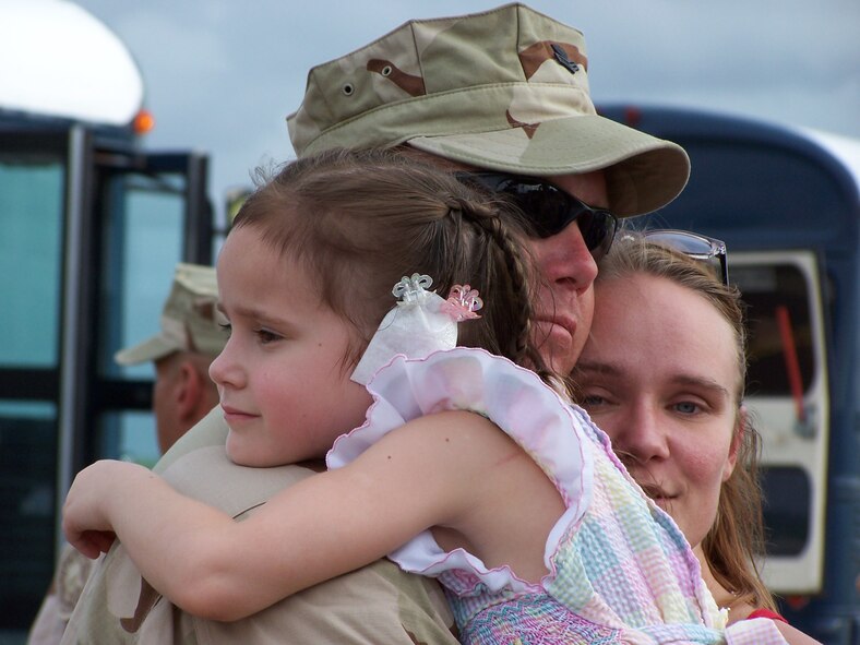 Petty Officer First Class Scott Kenneally, a member of the U.S. Coast Guard's Maritime Safety and Security Team Miami, gets a hugh from his fiance Heidi and her daughter upon his return from Guantanomo Bay, Cuba.  Approximately 50 members of the team deployed to GTMO on March 1 in support of Operation Enduring Freedom and Joint Task Force Guantanomo (U.S. Air Force Reserve photo by Lisa Macias).