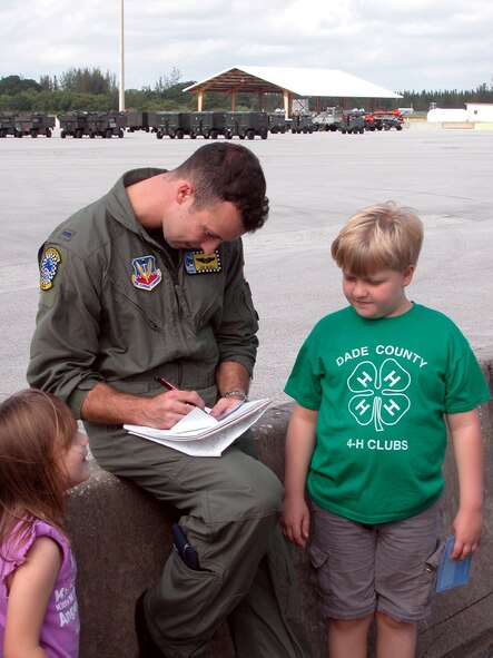 1st Lt. Joe McGill, an F-16 pilot with the 93d Fighter Squadron, signs autographs for Esther and John Coolidge of Miami's Pace homeschool enrichment program.  Lt. McGill volunteers as a tour guide for the 482d Fighter Wing's community relations program.  As a tour guide, Lt. McGill teaches students about the Air Force and how it might become part of their future (US Air Force Reserve photo by Jake Shaw).