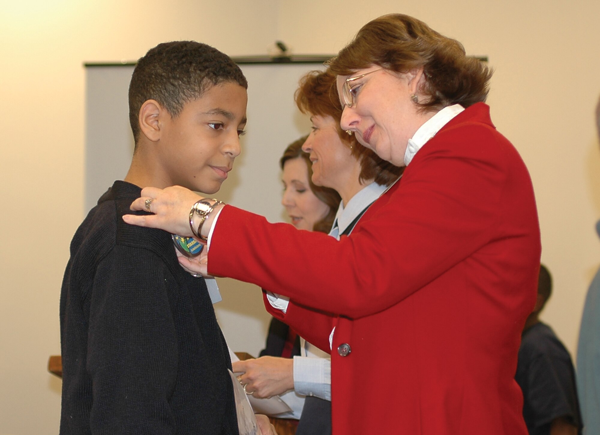 Mrs. Sheila Schencke, STARBASE Louisiana director, pins a STARBASE button on a Kerr Elementary student during his graduation Dec. 2. (USAF photo by Tech. Sgt. Sherri Savant)
