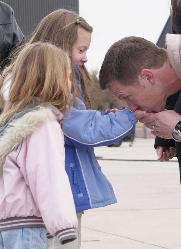 PETERSON AIR FORCE BASE, Colo. - Maj. Frank S. Wilde, Air Force Reservist and 731st Airlift Squadron navigator, kisses the hand of daughter Ellie while daughter Alyssa looks on as he prepares to leave for the Middle East Jan. 4. Major Wilde was on the first 302nd Airlift Wing deployment in 2006 in support of U.S. Central Command. (U.S. Air Force photo by Tech. Sgt. Tim Taylor)                   
