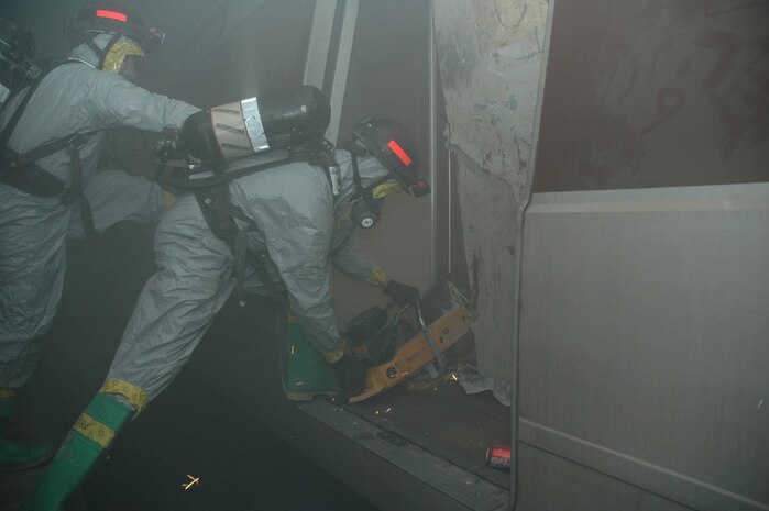 LANDOVER, Md.-Technical Rescue Marines with the Chemical Biological Incident Response Force Company B use a saw to cut through a subway car door during a simulated weapons of mass destruction attack at the Landover Metro Training Facility May 12.  After breaching the door the rescue team will triage and package all viable casualties trapped in the car.  The Marines wear Level B Personal Protective Equipment to protect them from contamination.