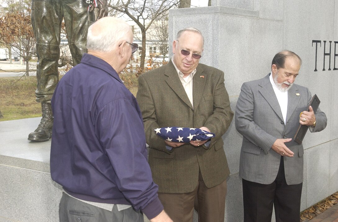 MARINE CORPS BASE CAMP LEJEUNE, N.C. - Ash Tyler, a retired Army chief warrant officer, hands Howard Kahn, the Marine Corps Interrogator Translator Team Association's second sub team commander, an American flag, which once hung in the 11th Interrogators Headquarters in Da Nang, Vietnam.  Tayler found the flag in the 11th Interrogators headquarters in Da Nang when the city was turned over to the Army during the Vietnam War. (Official U.S. Marine Corps photo by Staff Sgt. Michael Mink) (RELEASED)