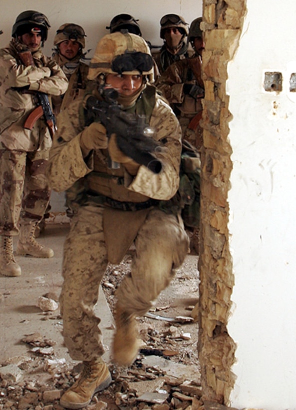 Lance Cpl. Jose D. Hernandez, a 21-year-old Los Angeles native and scout team leader, Company D, 1st Light Armored Reconnaissance Battalion, demonstrates to a group of Iraqi soldiers the proper technique for a one-man room clearing near Camp Korean Village. Hernandez his teammates, and the Iraqis were performing pre-combat rehearsals prior to a raid on a gas station. Marines are increasing the amount of time spent training their Iraqi counterparts to enhance the Iraqis' ability to fight the insurgency with minimal American assistance.