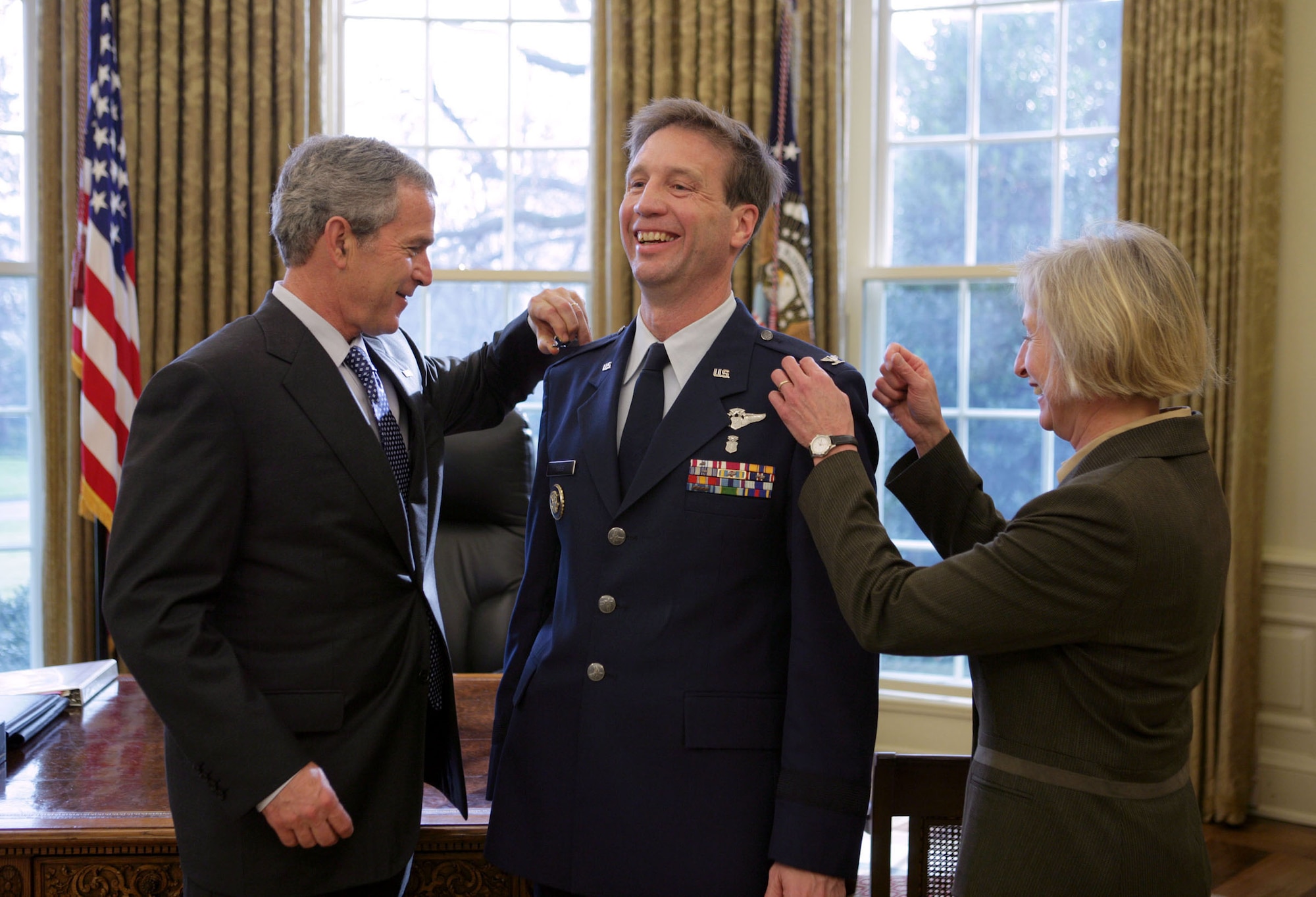 WASHINGTON -- President Bush removes Brig. Gen. (Dr.) Richard J. Tubb's eagles during the doctor's promotion ceremony in the Oval Office here today.  Dr. Tubb's wife, Kathy, also assisted with the ceremony.  Dr. Tubb, a U.S. Air Force Academy graduate, is the president's physician.   As the director of the medical unit, Dr. Tubb runs a staff of about 25 of the nearly 2,000 people assigned to the White House Military Office.  (White House photo by Paul Morse)