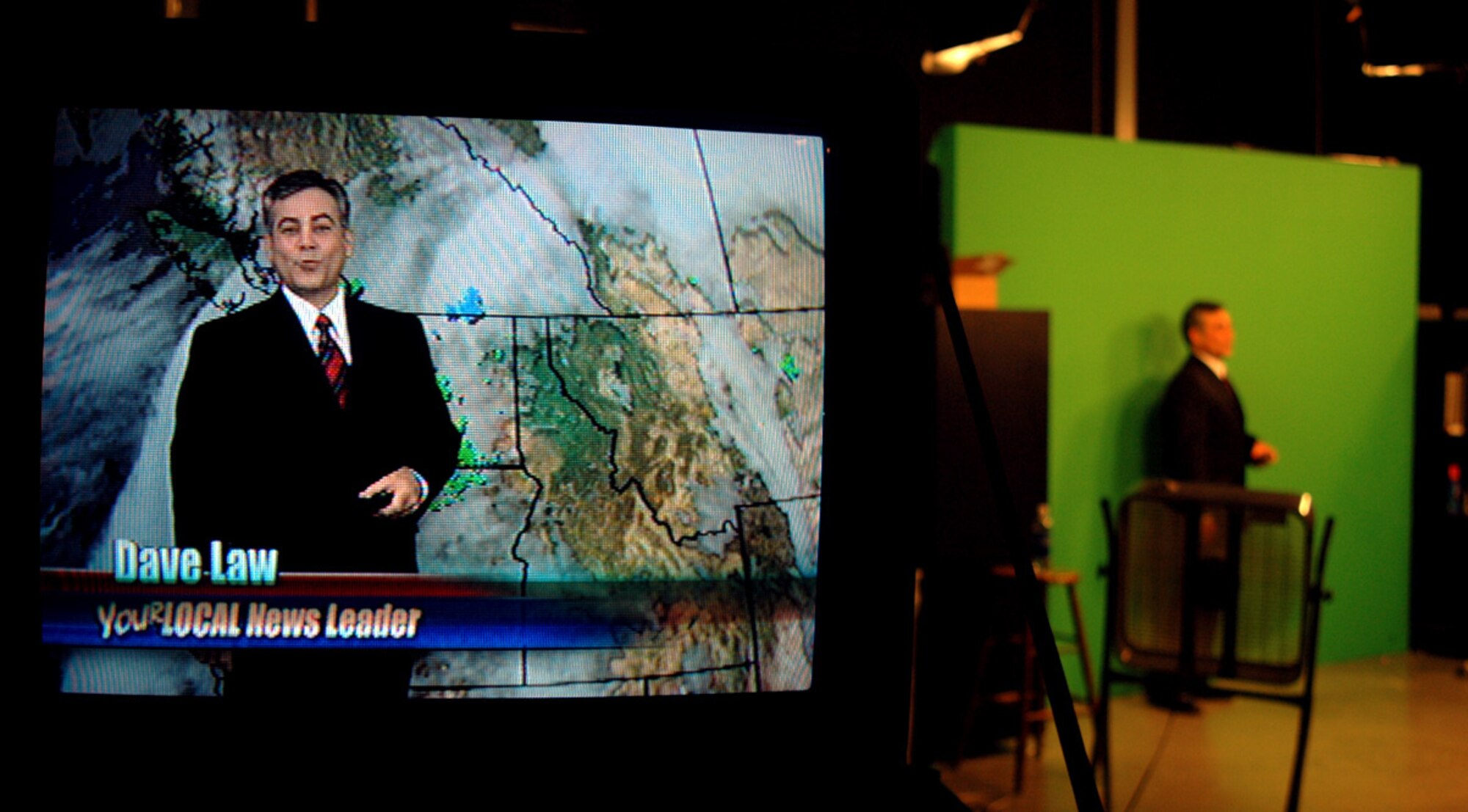 FAIRCHILD AIR FORCE BASE, Wash. (AFPN) -- Retired Master Sgt. Dave Law, broadcast weatherman, KHQ6, uses a "clicker" to switch backgrounds from one image to another during the course of his broadcast Jan. 6. He knows how much time is left by queues from the producer he receives through an earpiece. Dave Law retired from the Air Force in November after serving 23 years as a meteorologist. (U.S. Air Force photo by Staff Sgt. Nathan Gallahan)