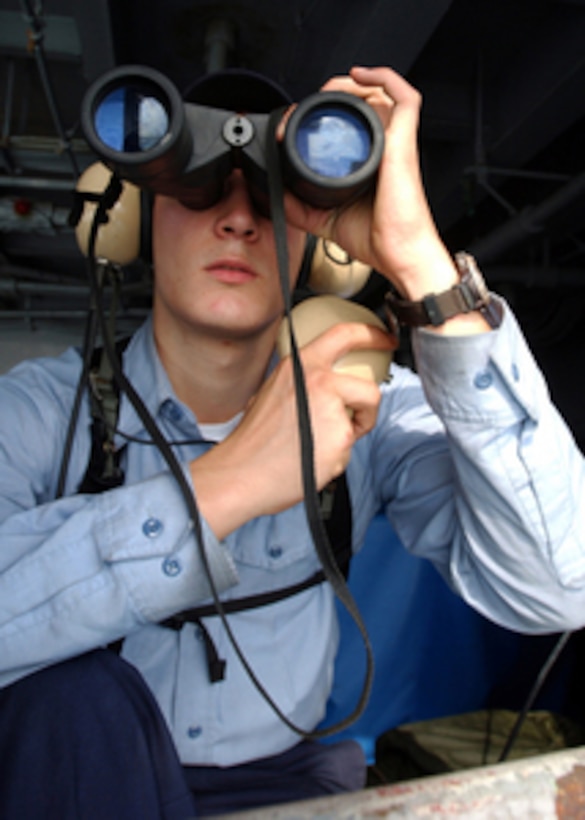 Navy Seaman Keith Ketterer uses his binoculars to search the horizon for any air or surface contacts while standing lookout watch aboard the aircraft carrier USS Theodore Roosevelt (CVN 71) during flight operations in the Persian Gulf on Jan. 12, 2006. Roosevelt and its embarked Carrier Air Wing 8 are conducting maritime security operations in the Persian Gulf. 