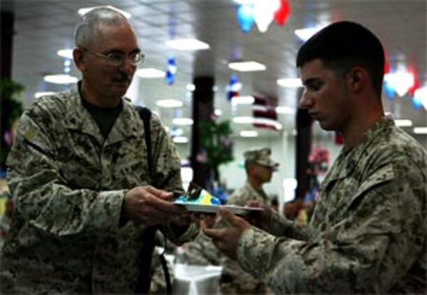 Navy Capt. Chuck Blankenship, a 57-year-old general surgeon with Taqaddum Surgical and a native of Texarcana, Tx. passed a piece of cake to Seaman Christopher L. Daniel, a 20-year-old native of Barnesville, Ga. and a corpsman with Military Police Company, CLR-15, 1st MLG.  When the oldest sailor passes the youngest sailor a piece of cake, it symbolizes the passing of tradition, said Senior Chief Ed Santa-Maria, Command Master Chief, 1st MLG.  It also symbolizes the passing of responsibility and the transference of values, so that the Navy remains the best in the world, said Santa-Maria, a 45-year-old native of Dededo, Guam.