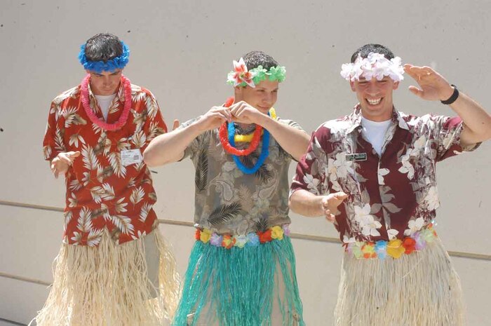 Petty Officer 2nd Class Andy Wilson (left), clinic pharmacy technician, Seaman Cody Weruen (center), clinic military medicine, and Petty Officer 3rd Class Benjamin Reyes, station corpsman, compete for hula dancing champion bragging rights. Reyes danced away as the champion saying the competition made him feel more like a man. The event also featured hula-hoop and ugliest Hawaiian T-shirt contests, new staff recognition and a presentation for a future sailor.