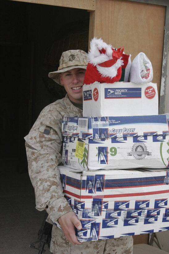 051225-M-2607O-001 - Seman Apprentice Kyle C. Mallard, Religious Program Specialist for 2nd Battalion, 2nd Marine Regiment, carries some packages filled with stocking to be loaded on a convoy for the Marines in the area of operation.