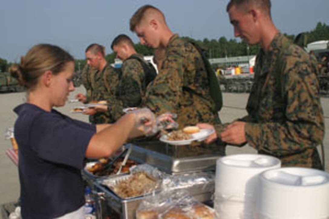 A caterer serves barbeque to Marines and Sailors of the 26th Marine Expeditionary Unit at a warriors' night at Fort A.P. Hill, Va., July 15, 2006.  The event was held to promote espirit de corps among the MEU's different elements, who have been training at Fort A.P. Hill since July 6 as part of a rigorous six-month pre-deployment training program.