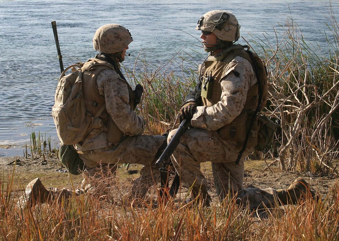 U.S. Marine Corps Lance Cpl. Miez, a radio operator, and Cpl. Brad Adams, both with Lima Company, 3rd Battalion, 1st Marine Regiment, watch each others back while on a security halt during a patrol down a riverbed in Barwana, Iraq, for any possible weapons caches Jan. 15, 2006. (U.S. Marine Corps photo by Cpl. Michael R. McMaugh) (Released)