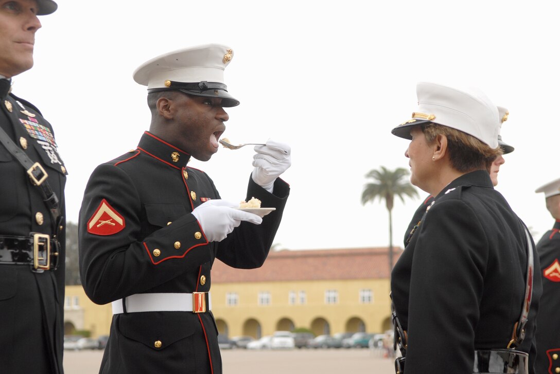 Lance Cpl. Townsend Milligan (center), quality control monitor and youngest Marine present, takes a bite of cake given to him by Col. Mark Callihan, chief of staff, Marine Corps Recruit Depot San Diego and the Western Recruiting Region and oldest Marine present. Brig. Gen. Angie Salinas (right), commanding general, MCRD San Diego and the WRR, passed the piece of birthday cake to Callihan, who passed it to Milligan in accordance with Marine Corps birthday tradition.