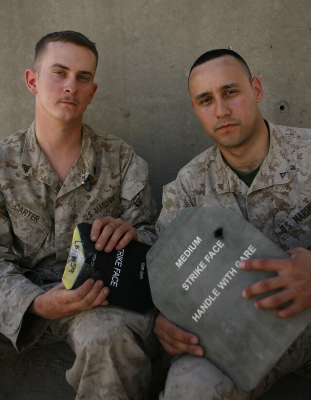 Cpl. Will D. Carter and Lance Cpl. Joel Salazar, with 1st Battalion, 1st Marine Regiment, show off the small-arms protective inserts that saved their lives.  Both Marines were shot within days of one another near Abu Ghraib prison in the battalion's area of operation while conducting anti-insurgent patrols.