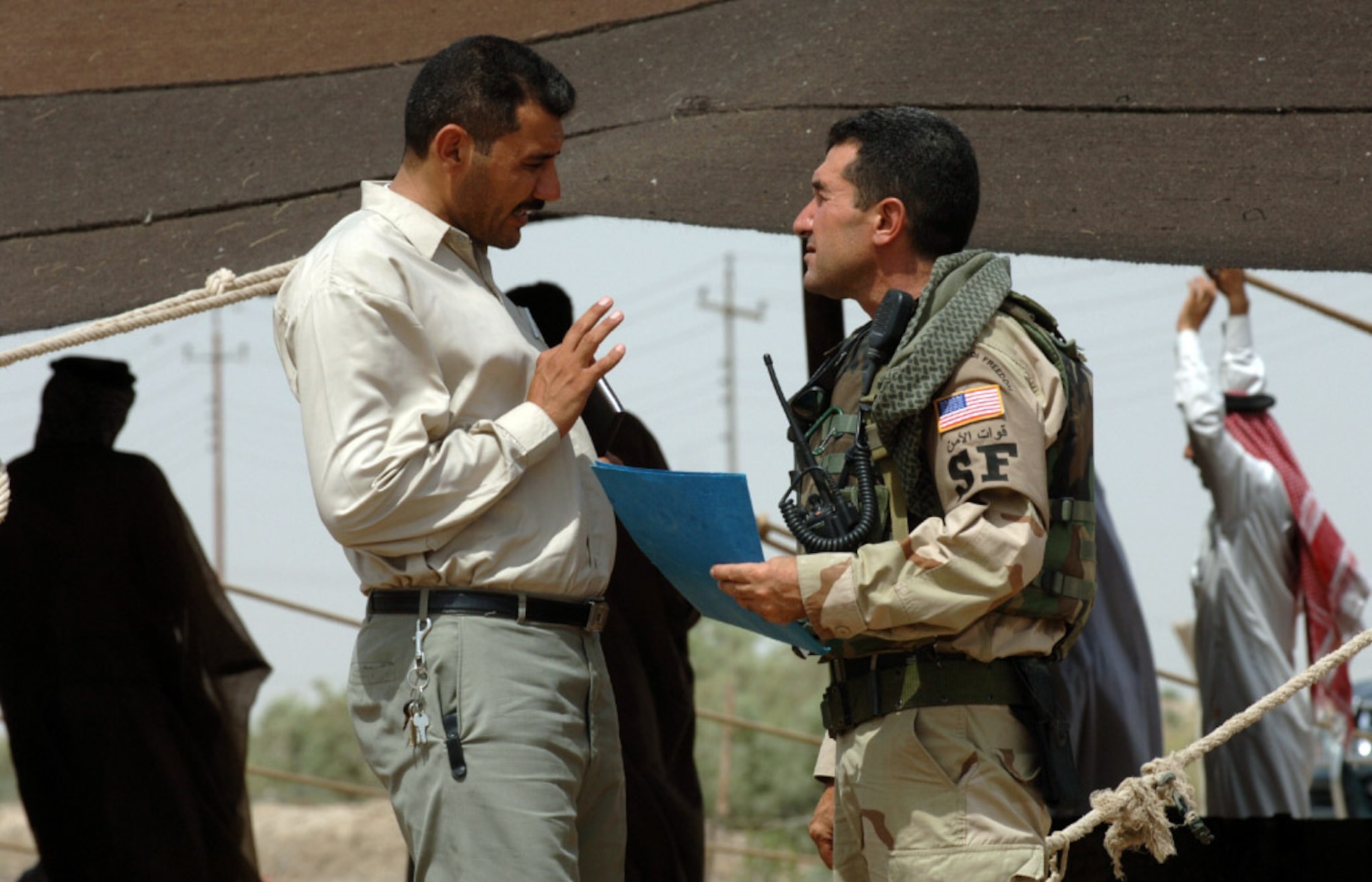 IRAQ -- Sam (right) talks to a local man. The Arab linguist talks to many leaders in the area, listening to their concerns and sharing ideas about the best ways to move forward. (His full name is not used for security reasons). (U.S. Air Force photo)