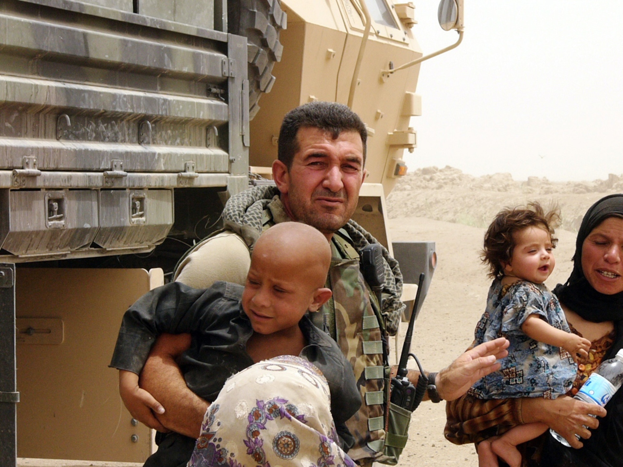 IRAQ (AFPN) -- Sam helps some local children. He has been involved in many projects aimed at helping the Iraqi people in the local area. Airmen and Soldiers sometimes join their resources to deliver aid to local communities. Many of the families are Bedouins, living off of the land, to which Saddam Hussein halted the flow of irrigation. (U.S. Air Force photo)