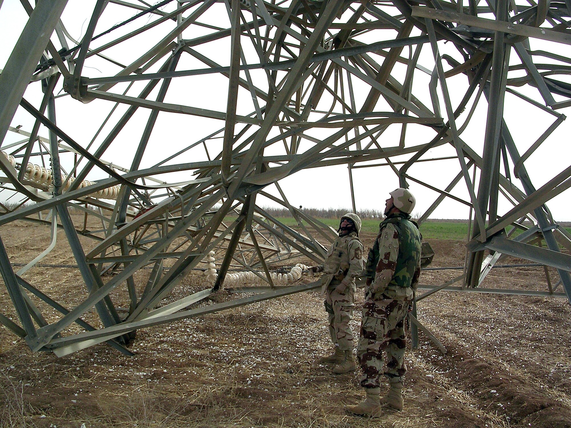 SOUTHWEST ASIA -- Chief Master Sgt. Paul Kaplan, the electrical infrastructure liaison officer, inspects a damaged high-voltage power line tower with an Iraqi Army officer. (U.S. Air Force photo)