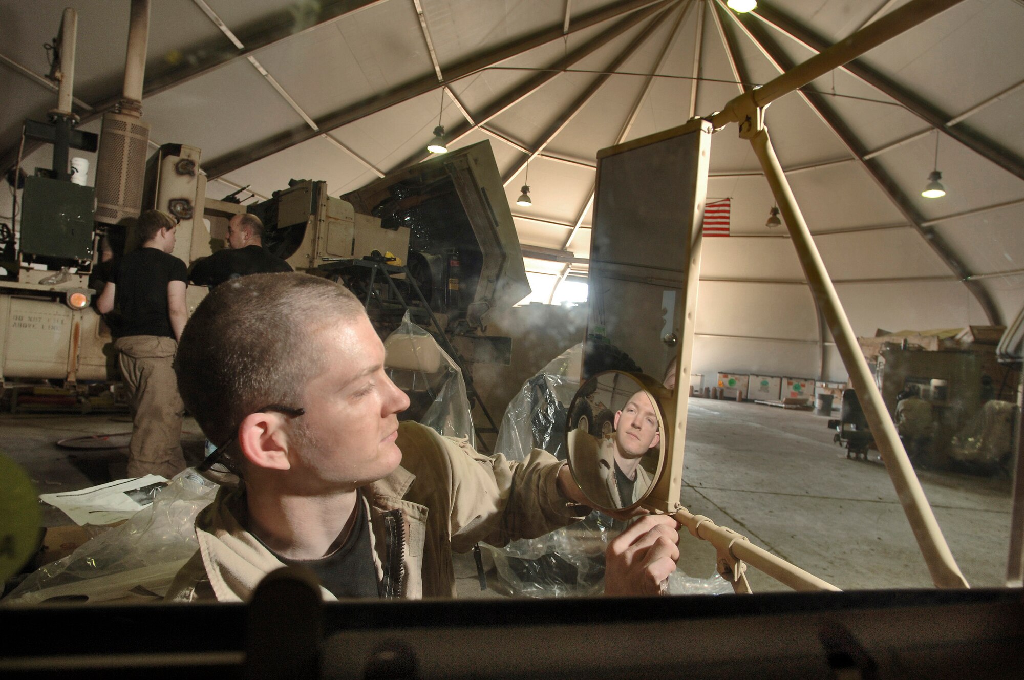 BALAD AIR BASE, Iraq -- Staff Sgt. John See puts the final touches on a rearview mirror of an armored cab at the add-on armor shop here. The armor provides the driver and gunner protection against weapons fire and improvised explosive device explosions. Sergeant See is deployed from Seymour-Johnson Air Force Base, N.C. (U.S. Air Force photo by Master Sgt. Lance Cheung)