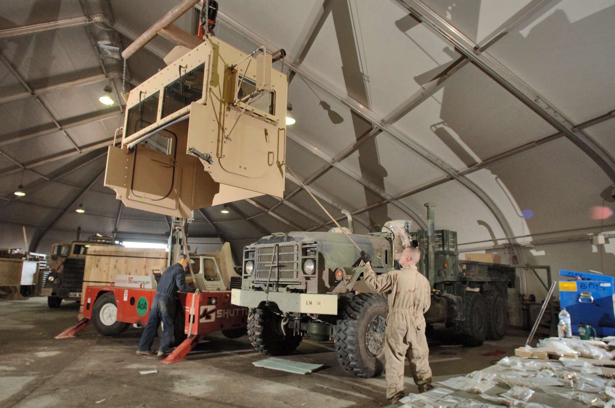 BALAD AIR BASE, Iraq (AFPN) - Airman 1st Class Roger Hild and Staff Sgt. Kenneth Pease operate a crane as they lower an add-on-armor cab onto the lower cab section of a truck tractor. The up-armor kit is a permanent modification. This will include new air ride seats and air conditioning. The armor provides the driver and gunner protection against weapons fire and improvised explosive device explosions. Sergeant Pease and Airman Hild are assigned to the 732nd Expeditionary Logistics Squadron and are deployed from Spangdahlem Air Base, Germany. (U.S. Air Force photo by Master Sgt. Lance Cheung) 