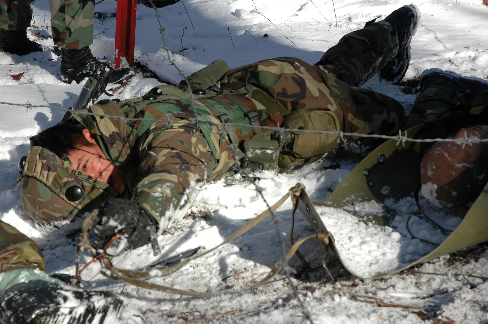 FORT DIX, N.J. (AFPN) -- Airman 1st Class Sam Alvarado drags a litter carrying a makeshift patient underneath barbed wire. The scenario was part of the Air Mobility Warfare Center's Integrated Contingency Skills Training here Jan. 15. More than 100 Airmen from Air Mobility Command are participating in this program, which compliments wing-level training programs around the command. Airman Alvarado is with the 43rd Security Forces Squadron at Pope Air Force Base, N.C. (U.S. Air Force photo by Staff Sgt. Bryan Bouchard)