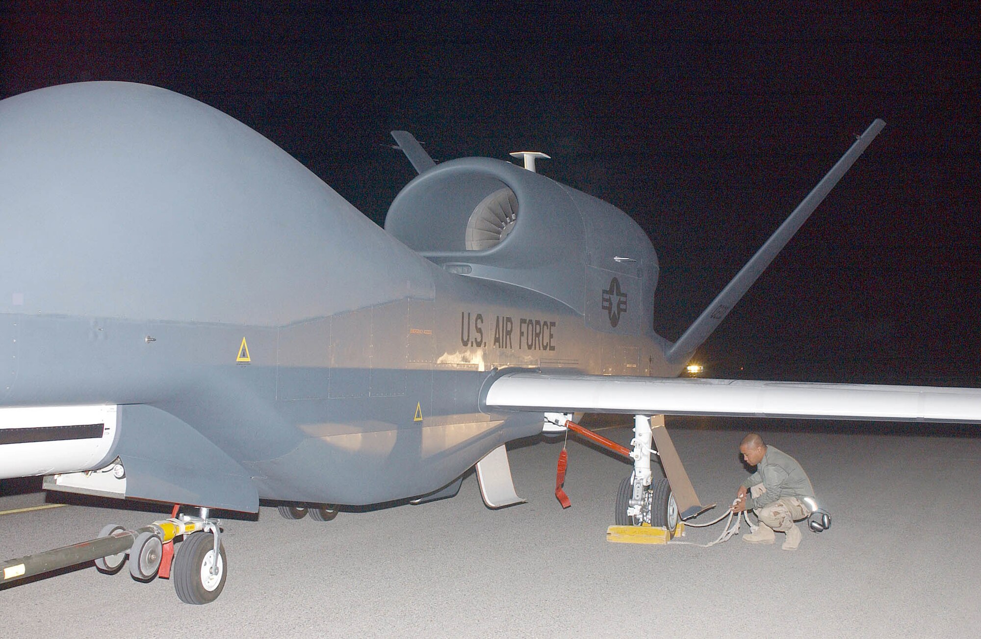SOUTHWEST ASIA (AFPN) -- Senior Airman Richard Griego puts chocks under a Global Hawk at a desert base. The unmanned aerial vehicle is the Air Force's first production Global Hawk and the first deployed. It has been upgraded from previous models. Airman Griego is an avionics technician with the 380th Expeditionary Aircraft Maintenance Squadron and deployed from Beale Air Force Base, Calif. (U.S. Air Force photo by Tech. Sgt. Glynis Fresia)

