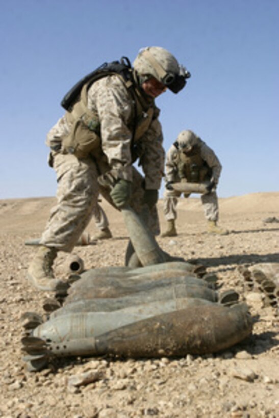 U.S. Marines from Lima Company, 3rd Battalion, 1st Marine Division, work with U.S. Navy sailors from Explosive Ordnance Disposal Mobile Unit 6 to stack rockets, mortars, and bags of propellant that were found buried in the ground on the outskirts of Barwana, Iraq, on Jan. 15, 2006. The rockets, mortars, and propellant will be destroyed with C-4 plastic explosive to prevent their use in improvised explosive devices. 