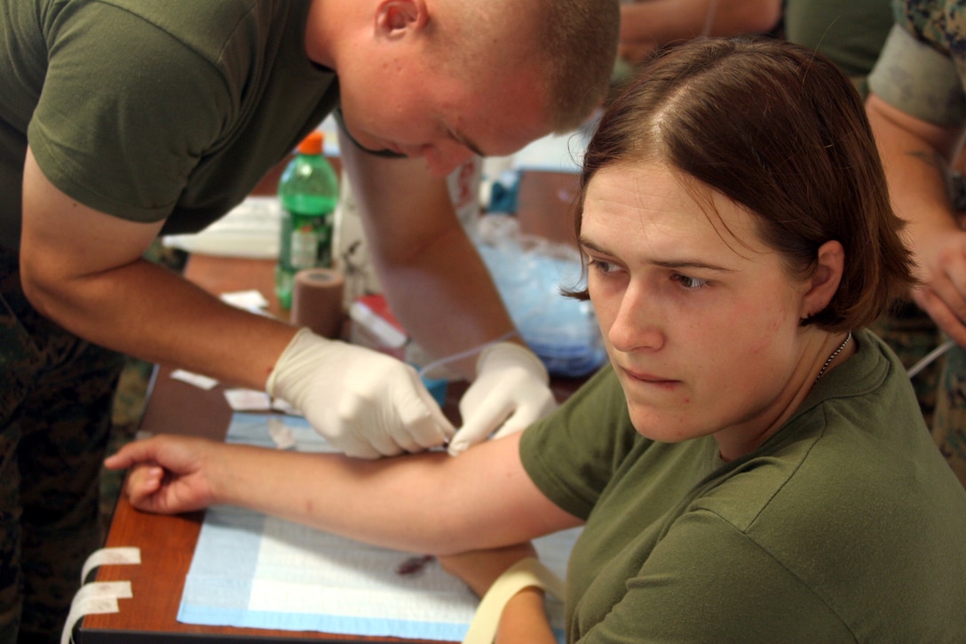 MARINE CORPS BASE CAMP LEJEUNE, N.C. (July 11, 2006) - Unable to watch as the 20-gauge needle is being inserted into her vein, Lance Cpl. Felicia M. Kent, a motor transportation operator with Truck Company, Headquarters Battalion, 2d Marine Division, bites her bottom lip and braces for the pain. During the "stab lab" portion of the Combat Lifesaver Course, learn how to properly start an intravenous line.