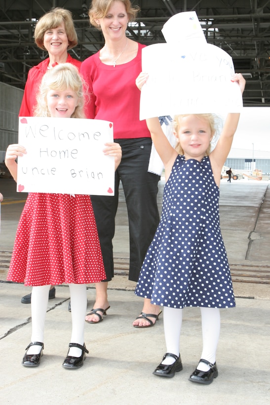 Kaitlyn Pastino, 5, and Meghan Pastino, 3, hold up ?welcome home? signs while waiting for the return of their uncle, Maj. Brian N. Pinckard, Oct. 18. Pinckard and his team provided operational airlift support during a deployment to Al Udeid Air Base, Qatar in support of the Global War on Terrorism.