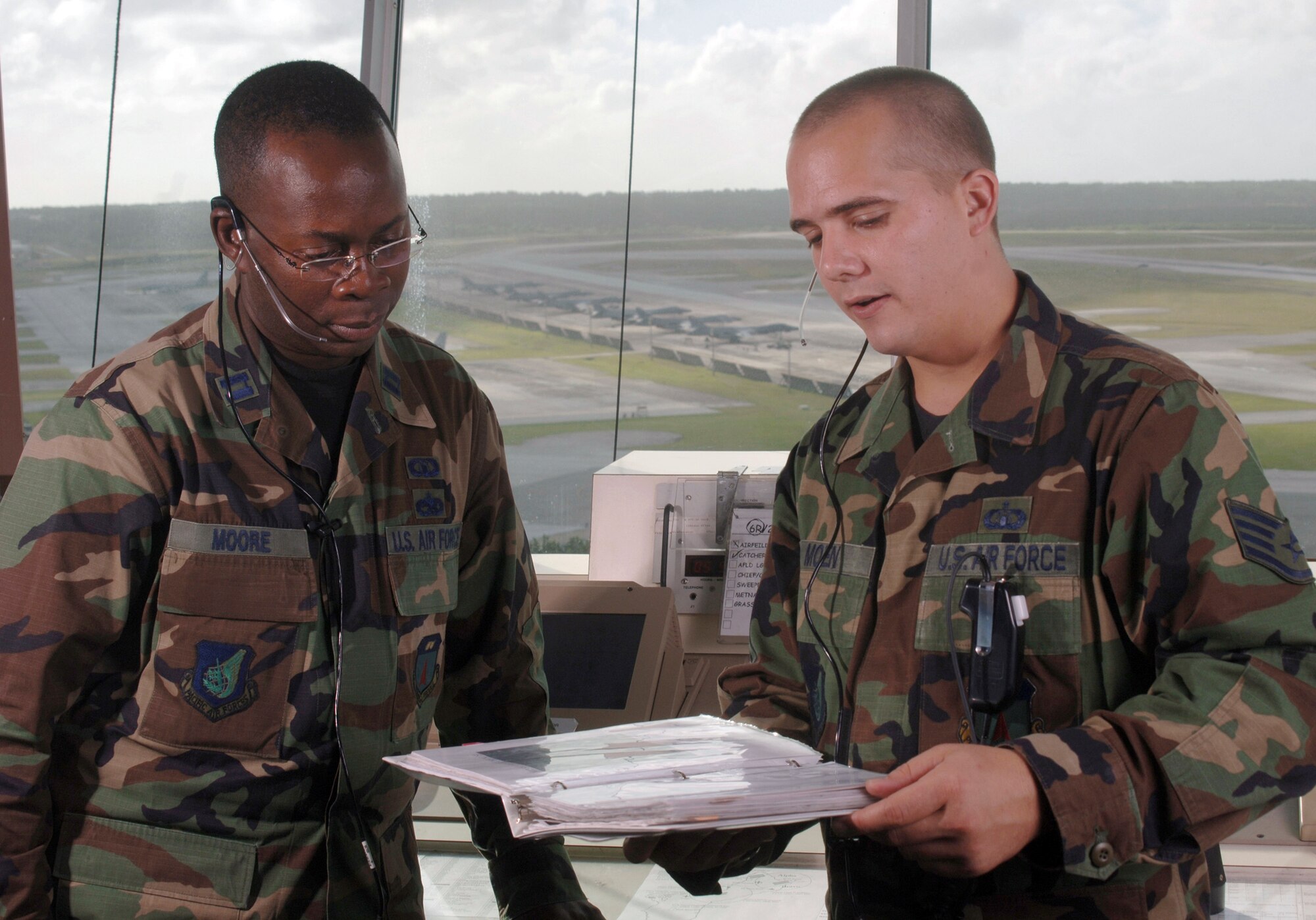 ANDERSEN AIR FORCE BASE, Guam (AFPN) -- Staff Sgt. Jesse Moen (right) briefs Capt. Marquette Moore on the status of arriving and departing deployed aircraft at the control tower here. Sergeant Moen is an air traffic controller, and Captain Moore is an operations flight commander with the 36th Operations Support Squadron. The Airmen coordinate movements of military and commercial aircraft through radar and visual observation. They closely monitor each plane to ensure safe distance between aircraft. (U.S. Air Force photo by Master Sgt. Val Gempis)
