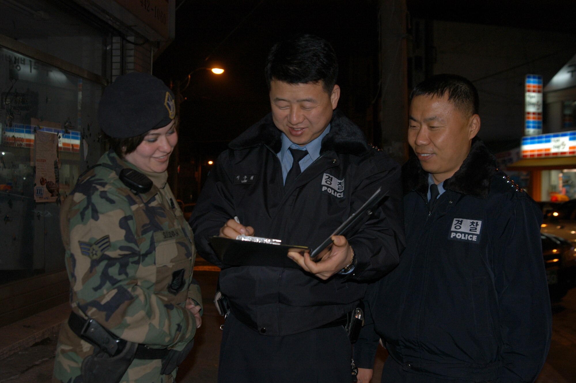 KUNSAN CITY, South Korea (AFPN) -- Senior Airman Shannon Sullivan, 8th Security Forces Squadron Town Patrol member, reviews police reports with Korean National Police Sergeants YI, Ku Hui (center) and YI, Kwon Tae. The 8th SFS, together with their KNP counterparts, now conduct patrols of downtown Kunsan City.  (U.S. Air Force photo by Airman 1st Class Stephen Collier)
