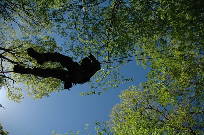 INDIAN HEAD, Md. - Cpl. Ronald R. Seaver dangles high above the ground during the execution of a midpoint drop during training at the Naval Support Facility Indian Head located here April 19.  During a rope rescue the technician is attached to a pulley system that has been constructed over a victim who cannot be rescued by simply walking down to where they are trapped and injured, as in the case of a ravine.  After the rescue platoon Marine is centered over the victim he is lowered down to them by executing a midpoint drop.  Once the technician has made contact with the victim he must assess the severity of injuries and decide the most efficient and expedient way to package the victim for rescue.