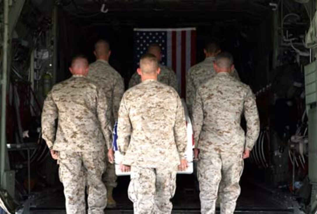 CAMP TAQADDUM, Iraq (July 20, 2006) - Marines of the Personnel Recovery and Processing unit at Camp Taqaddum, Iraq, carry the remains of a fallen service member into a waiting aircraft at Camp Taqaddum?s airfield for transportation to the United States. The mission of PRP is to inventory the personal effects, identify the types of wounds sustained, and prepare the remains of service members killed in the Al Anbar province for transportation to Dover Air Force Base. The Marine Corps? Personnel Retrieval and Processing units, formerly known as mortuary affairs, serve as a stepping stone on the journey home for those killed while serving in what is arguably the most dangerous province for U.S. service members in Iraq. Called PRP for short, the units are made up of 51 reserve Marines and sailors from various units and job fields. At Camp Taqaddum, a main logistics base located between Fallujah and Ramadi, the Marines have converted an old Iraqi Air Force hangar into the processing center for those killed in the Sunni-dominated area west of Baghdad.