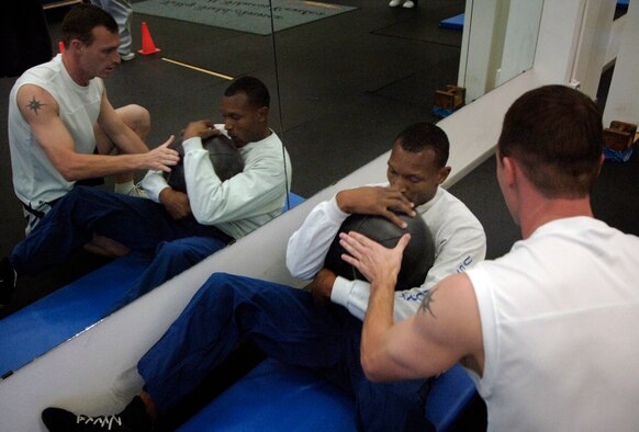 SAN ANTONIO (AFPN) -- Staff Sgt. Kelvin Leggett receives help from Staff Sgt. John House while performing core training at the Air Force Boxing Training Camp. Twenty-four Airmen our trying out for the nine spots to represent the Air Force at the Armed Forces Tournament.  Sergeant Leggett is assigned to the Headquarters Southern Command and Sergeant House is at Lackland Air Force Base, Texas.  (U.S. Air Force photo by Tech. Sgt. Larry A. Simmons)