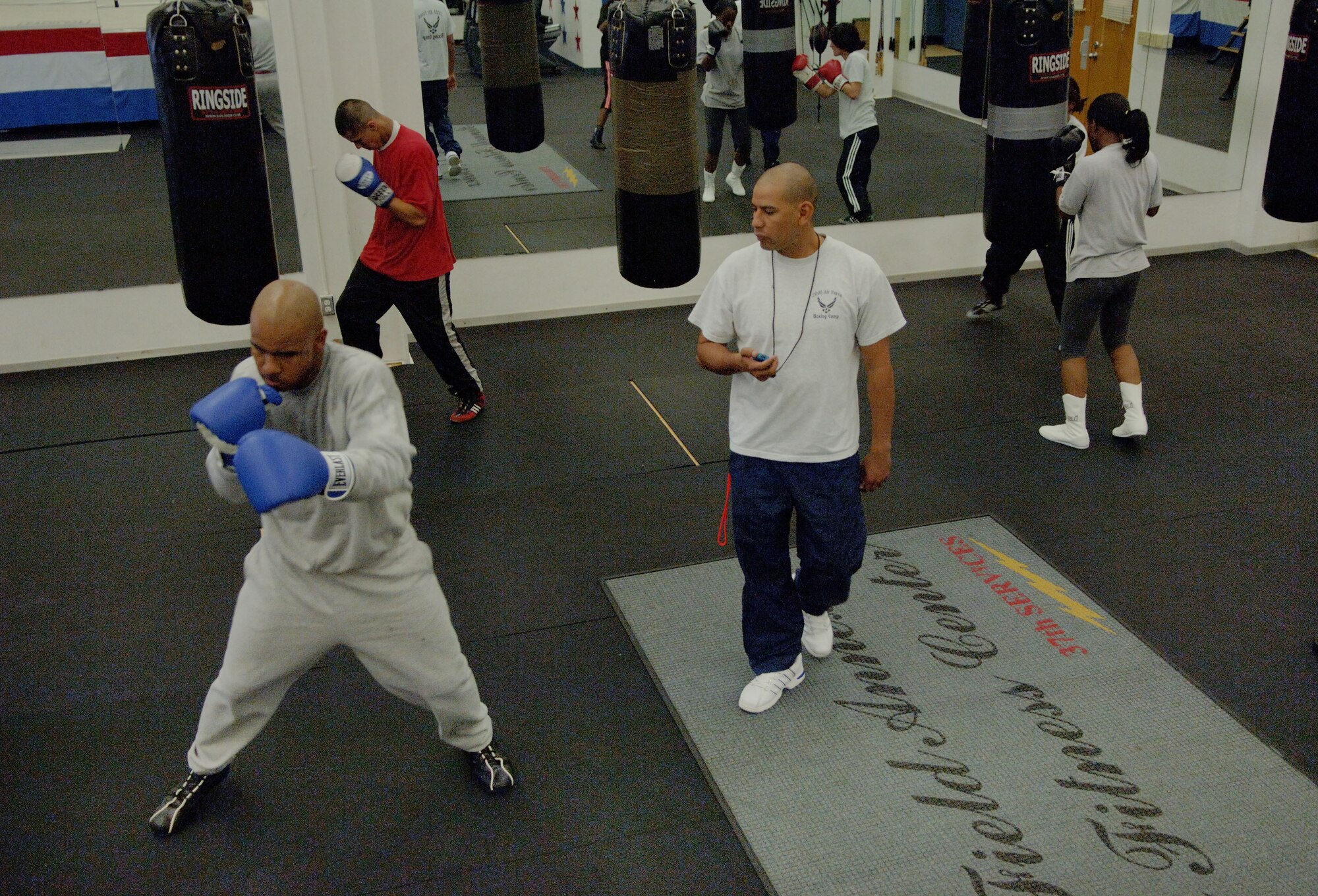 SAN ANTONIO (AFPN) -- Airmen practice boxing drills while Tech. Sgt. Rudy Moreno (middle), assistant coach, instructs them at the Air Force Boxing Training Camp. Twenty-four Airmen are trying out for the nine spots to represent the Air Force at the Armed Forces Tournament.  (U.S. Air Force photo by Tech. Sgt. Larry A. Simmons)