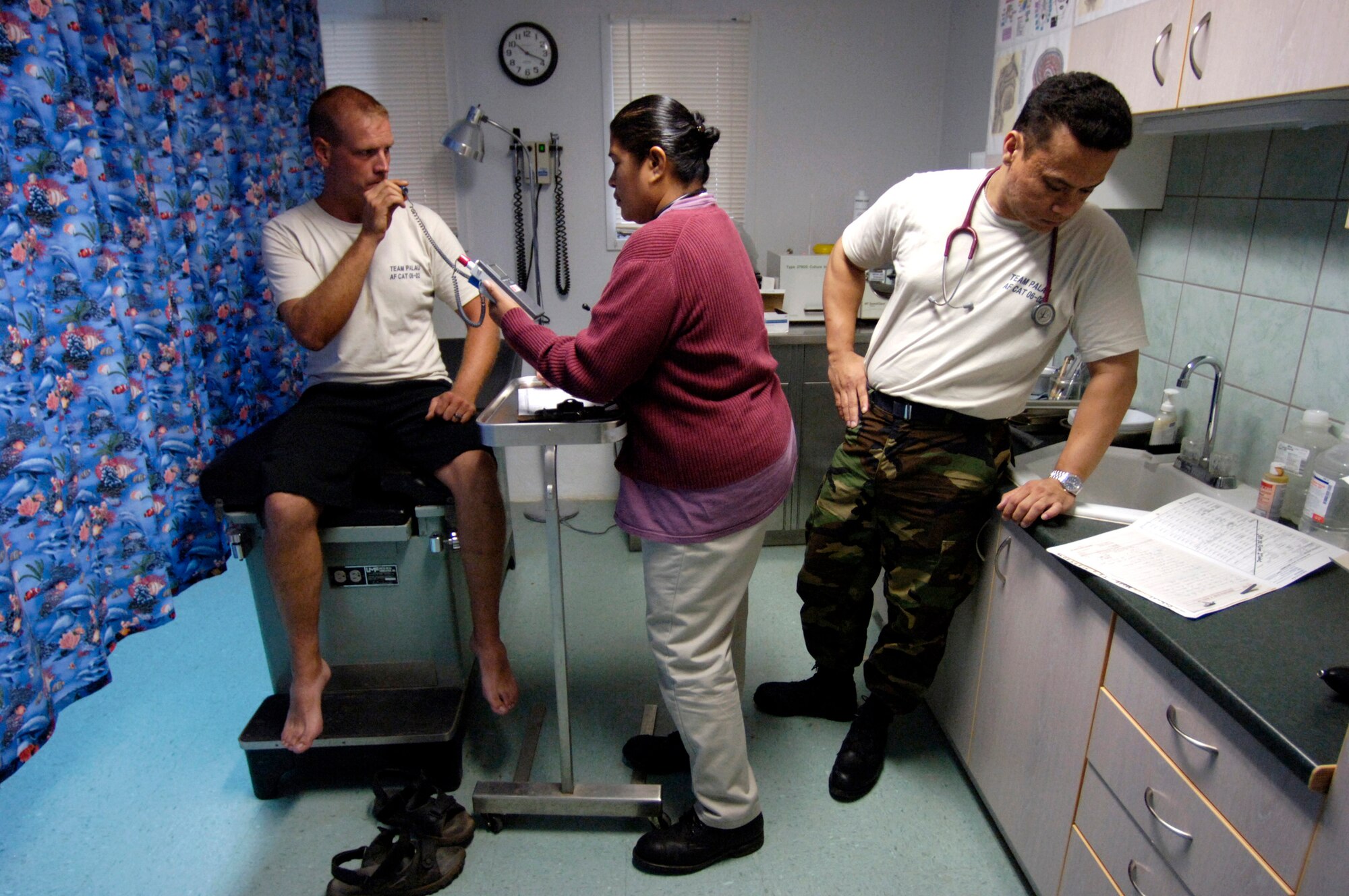 BABLEDAOB, Palau (AFPN) -- Capt. Dan Calderon, looks over a chart while his Palauan apprentice, Georgia Renguul, takes Tech. Sgt. Matt Schott's temperature. Captain Calderon and Sergeant Schott are from the Palau civic action team. The mission of the program is twofold. It aids host nations in their basic infrastructure development and it provides a favorable U.S. military presence through community construction, apprentice training, a medical civic action program and community relations. (U.S. Air Force photo by Tech. Sgt. Shane A. Cuomo) 