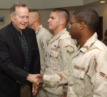 SOUTHWEST ASIA (AFPN) -- Former President George H. W. Bush, shakes hands with Airman 1st Class Christopher Trotter during the former president's visit this week to a deployed location in Southwest Asia.  Airman Trotter is deployed from Spangdahlem Air Base, Germany.  To his right is Airman 1st Class Joseph Smigielski, deployed from Dyess Air Force Base, Texas. (U.S. Air Force photo by Airman 1st Class Anthony Nelson)