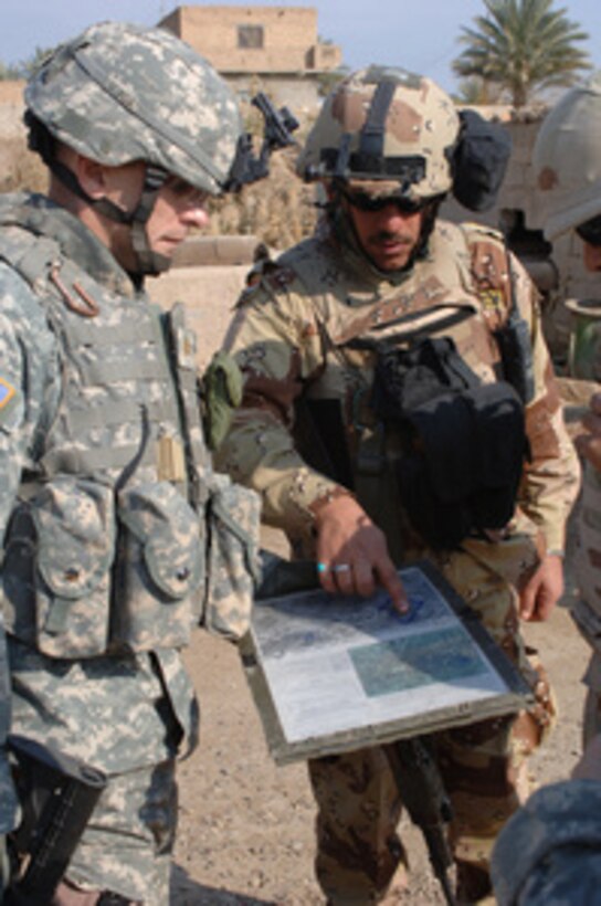 An Iraqi Army soldier (center) with the 9th Mechanized Brigade discusses tactics with U.S. Army Maj. Donny Yates (left) during a cordon and search mission in Hadem Mutleg, Iraq, on Jan. 18, 2006. Yates, and his fellow soldiers of the 1st Battalion, 66th Combat Aviation Brigade, 4th Infantry Division, are working jointly with the Iraqi Army to disrupt insurgent activity. 