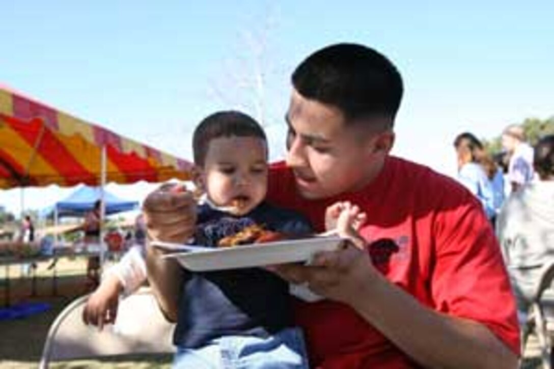 Sgt. Jonh A. Saracy, a Communications Company platoon sergeant with Brigade Service Support Group 1, shares his lunch with his son Jonh Jr, 14 months, at the BSSG-1 barbecue at Lake O' Neill. The Marines of BSSG-1 took an afternoon away from their shops and offices to enjoy good food, live entertainment and great company before they deploy to Iraq.