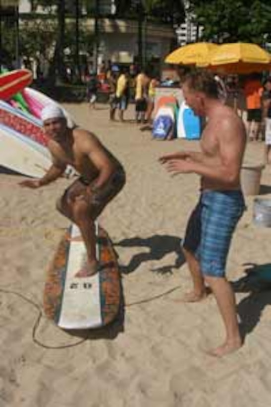 Lance Cpl. Nick Howes, combat photographer, Combat Camera, Headquarters Battalion, MCB Okinawa, Japan, gives his friend Ken Miles a few helpful tips on surfing before hitting the waves in Waikiki Beach in Honolulu Aug. 20.