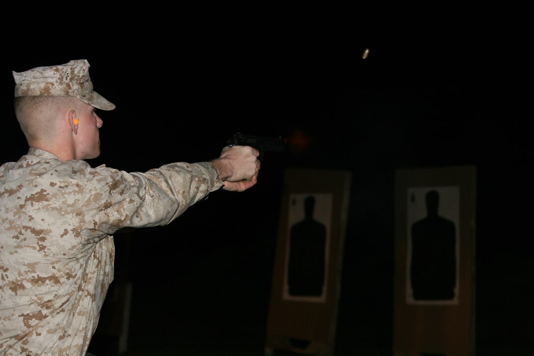 Lance Cpl. Jared Martin, a canine handler with the Headquarters and Headquarters Squadron Provost Marshal?s Office, fires a round at his target during annual low-light weapons training conducted at the Station pistol range, Feb. 28.