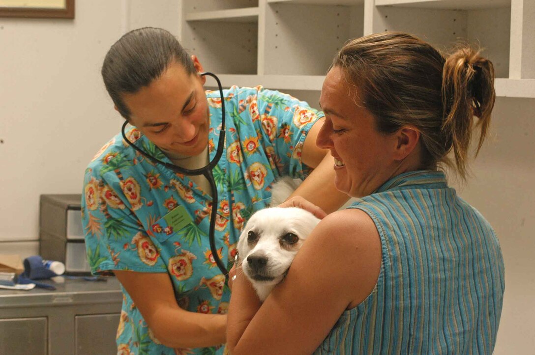 Army Capt. Renee Anderson (left), station and Yuma Proving Ground veterinarian, gives Mija, a 12-year-old American Eskimo dog, a brief check-up before giving her the Parvo/Temper vaccination at the station vaccination clinic April 21. The clinic saw 39 animals, gave 65 vaccinations, sold 20 dog licenses and handed out dozens of ID tags.