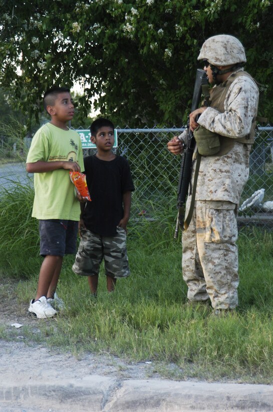 A Marine from 2nd Platoon, 1st Battalion, 23rd Marine Regiment, hands out candy to local children in San Diego, Texas, during urban warfare training July 22.
