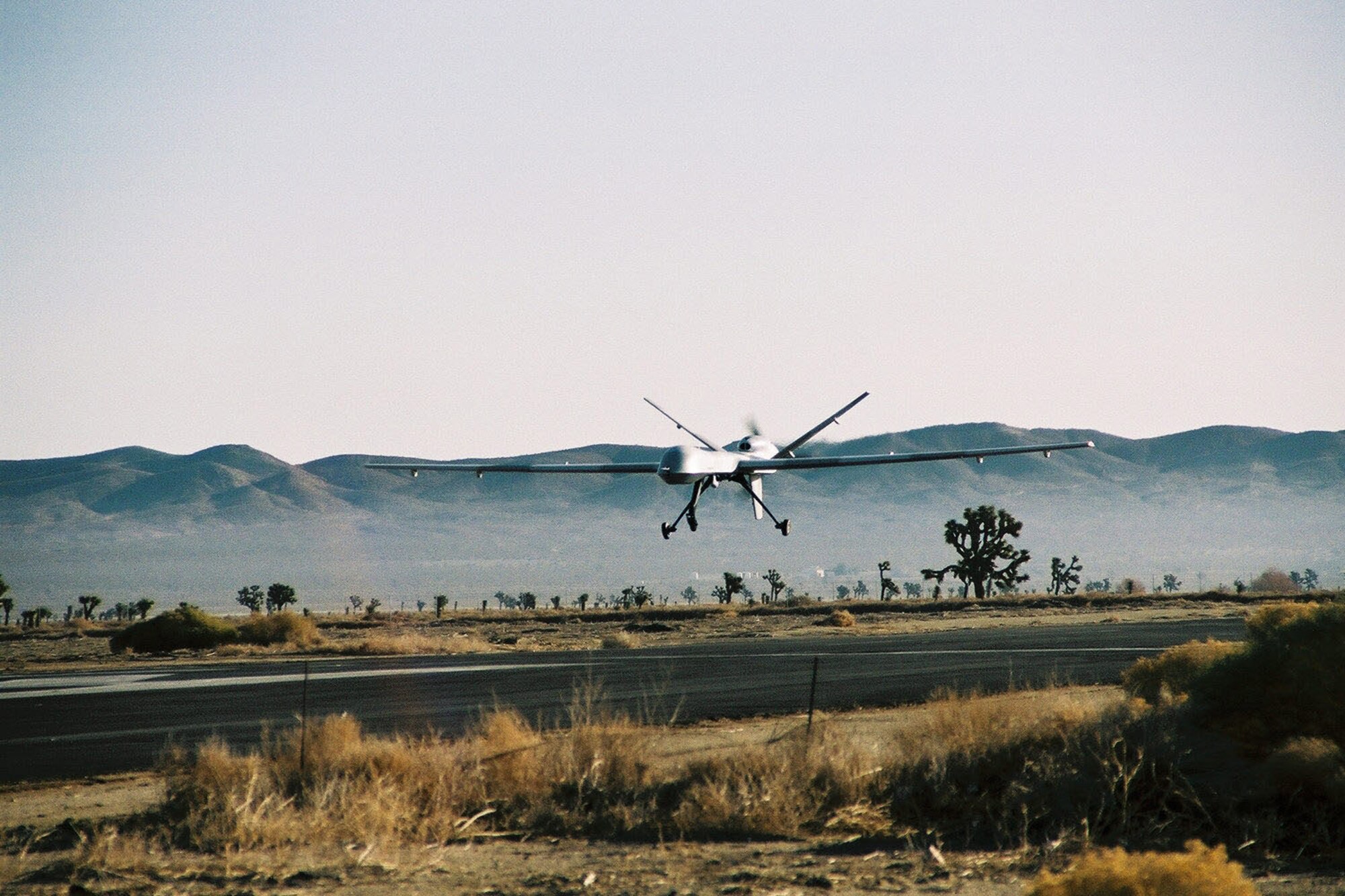 A Predator Unmanned Aerial Vehicle (left) lands at Gray Buttes-El Mirage test facility about 20 miles southeast of the base.  A Predator B UAV (right) flies over the Mojave Desert. The Predator A and B weapons systems are undergoing developmental test and evaluation by the newly-formed Detachment 1 of the 452nd Flight Test Squadron.  (Courtesy photos)

