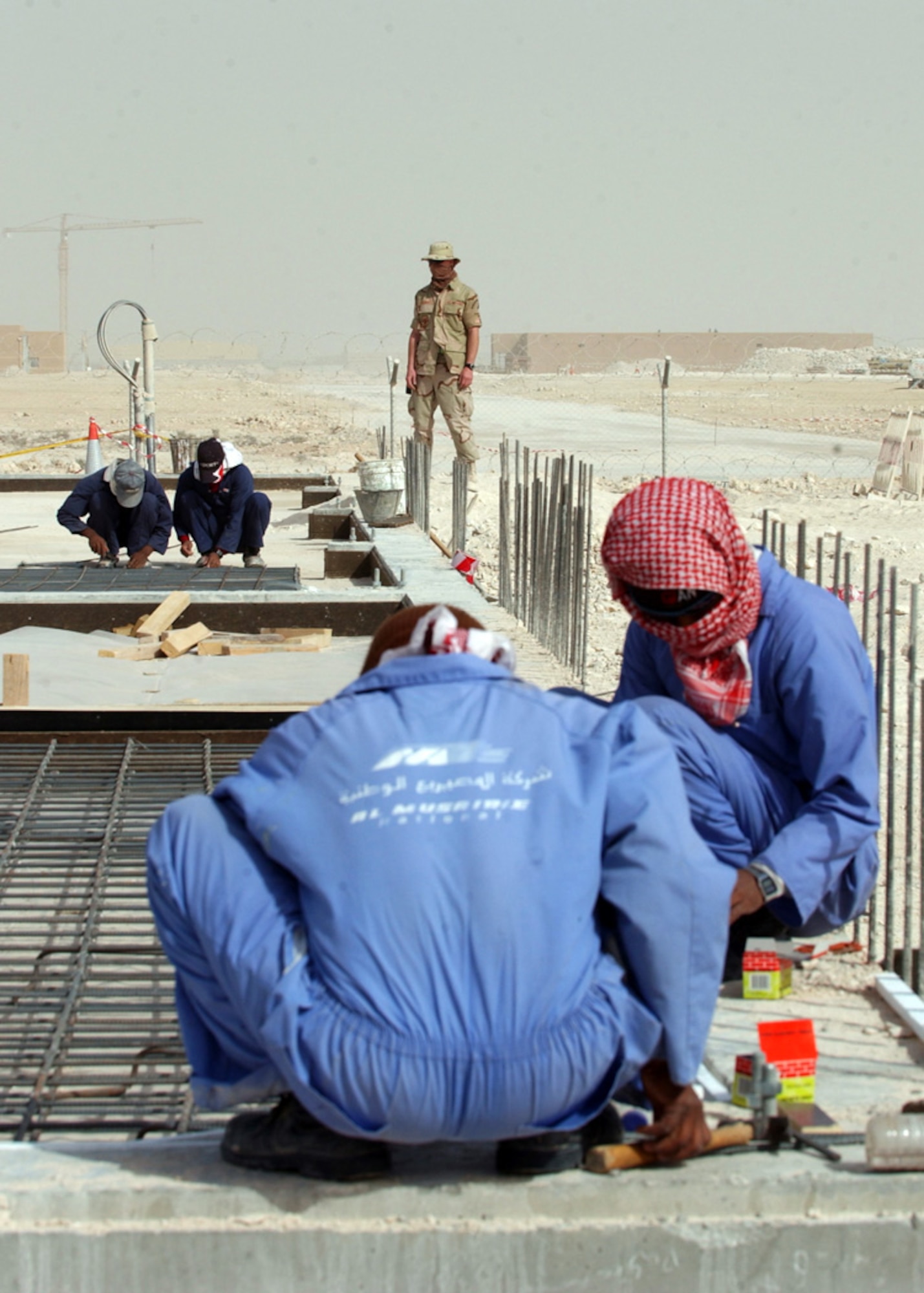 SOUTHWEST ASIA (AFPN) -- Senior Airman Christopher Peters watches third country national contractors build a new structure at a deployed location on Jan. 22. Airman Peters a third country escort with the 379th Expeditionary Civil Engineer Squadron is deployed from Langley Air Force Base, Va. (U.S. Air Force photo by Staff Sgt. Joshua Strang)